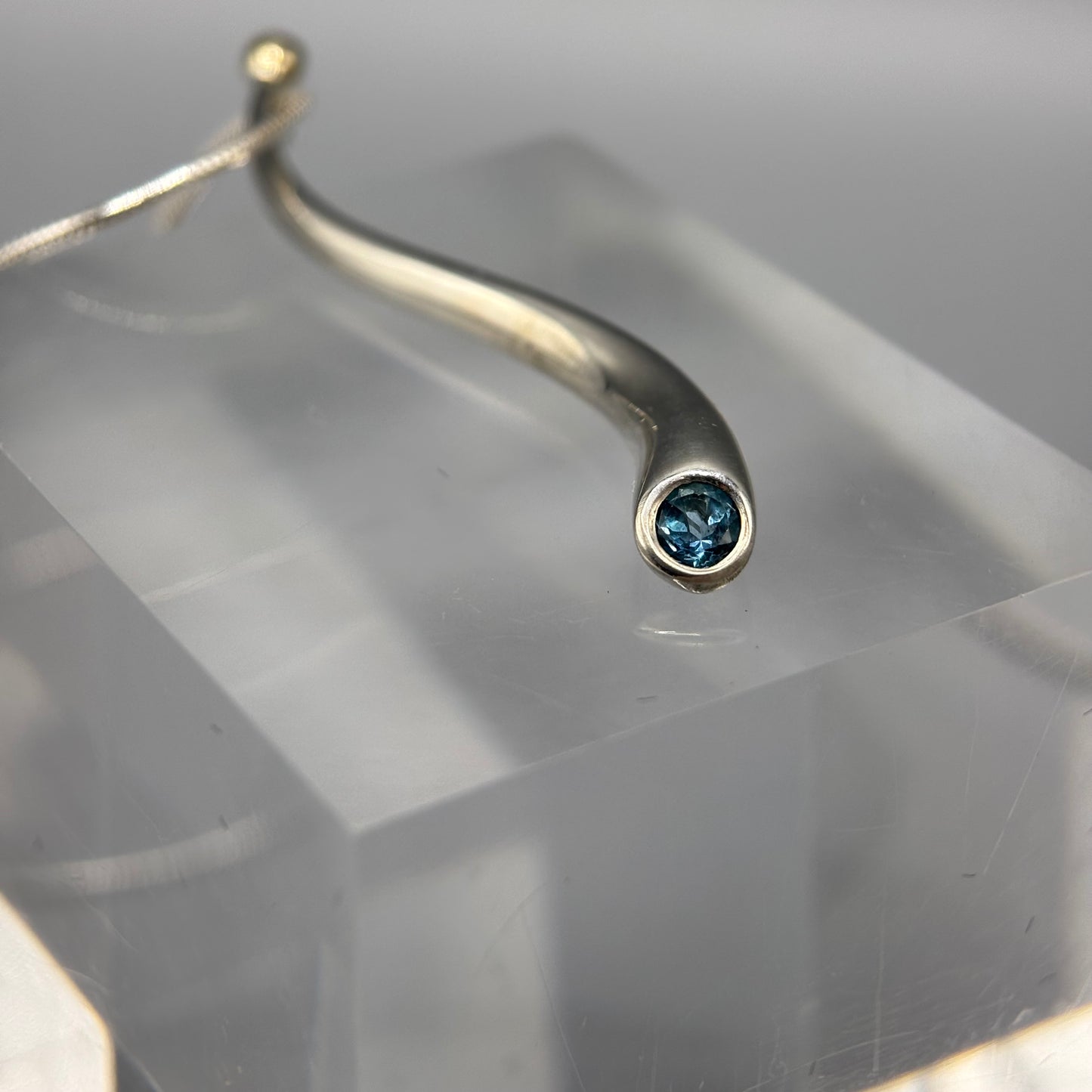 Paul Finch - Pendant: Curving solid silver with blue topaz & solid 18ct Yellow Gold bead